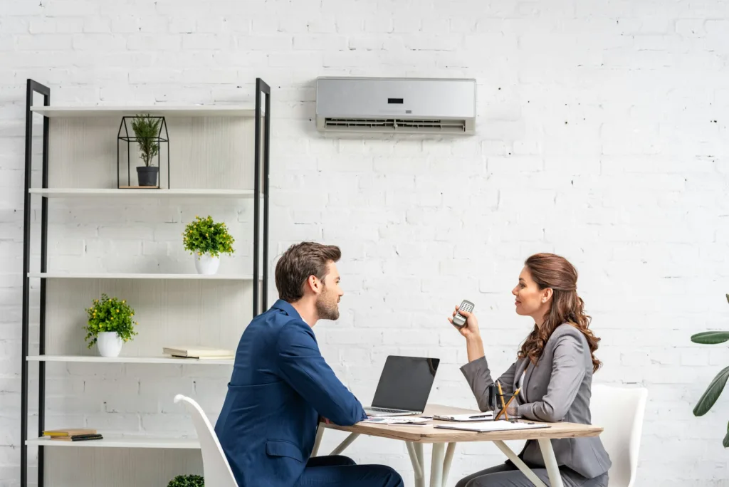 business partners talking while sitting at workplace under air conditioner