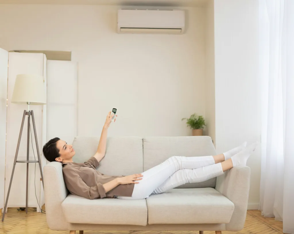 Young woman switching on air conditioning at her house